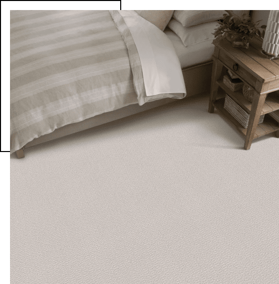 Cozy bedroom corner with beige bedding and wooden nightstand.