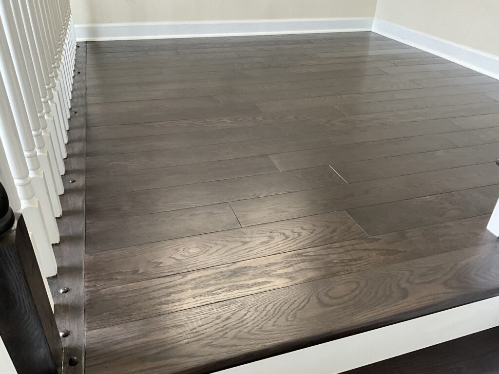 Empty room with dark wood flooring and white baseboards.
