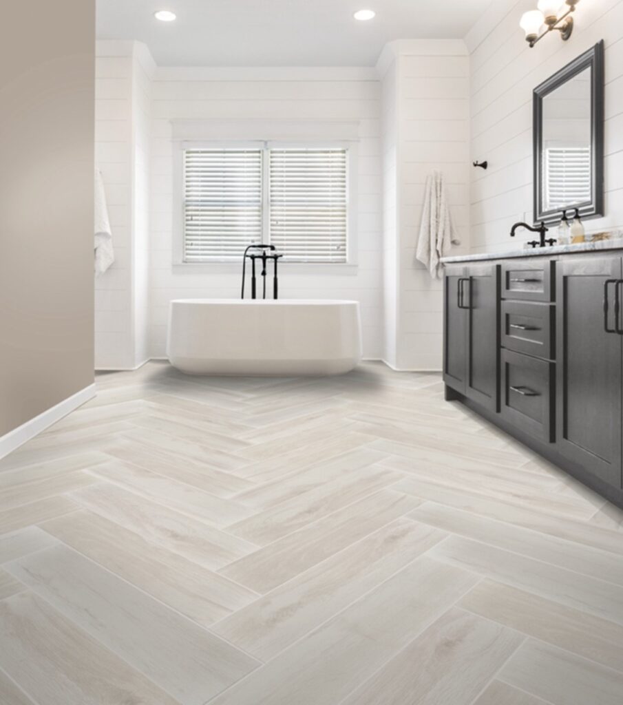 Modern bathroom with herringbone tile flooring and a freestanding bathtub.