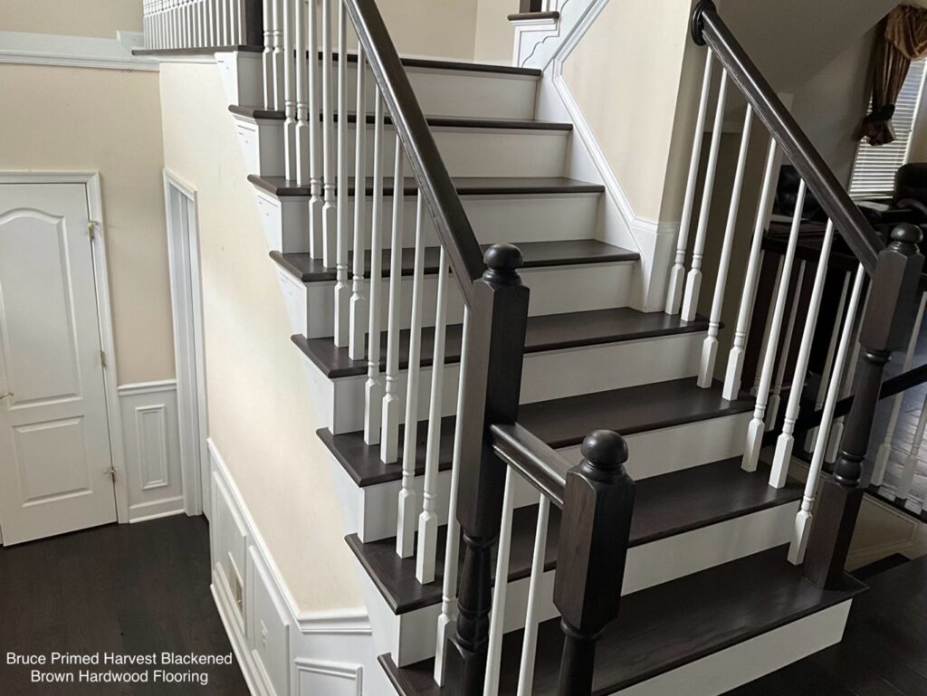 Modern staircase with dark wood steps and white railings in a bright home.